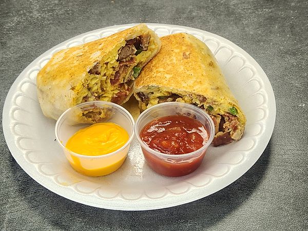 A breakfast burrito cut in half on a plate, with a cup of cheese sauce and a cup of salsa