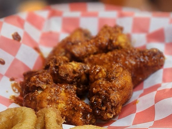 Crispy wings tossed in hot sauce in a red-checkered basket